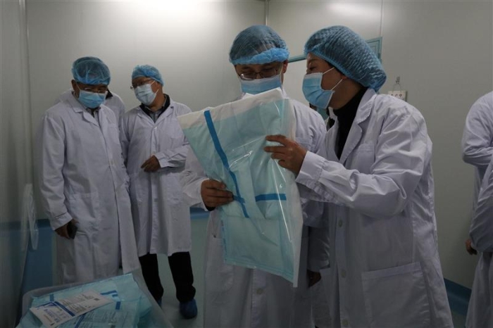 图为云南省药监局党组书记、局长刘本军（右二）检查该企业生产的医用一次性防护服。（云南省药监局供图）