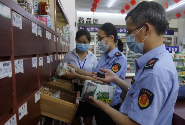 图为执法人员在一家零售药店检查中药饮片。