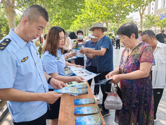 图为工作人员向群众发放禁毒宣传手册。