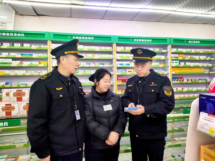 图为2月4日，执法人员在一家药店通过标签标识核查药品质量